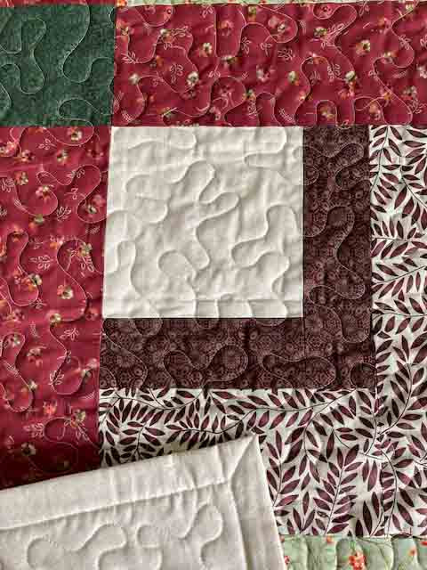 Corner Square Handmade Quilt with red, green, and brown close up