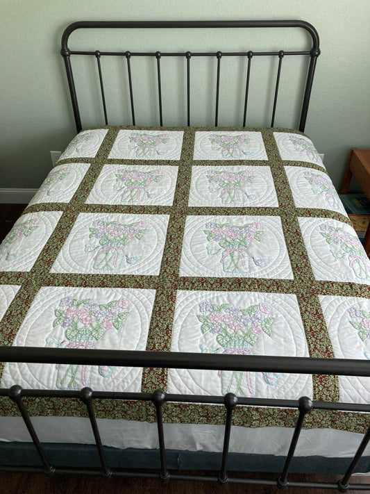 handmade embroidered quilt with pastel flowers in mason jars