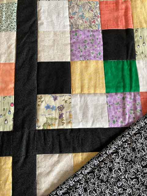 handmade quilt colorful squares pixels orange green purple black yellow close up