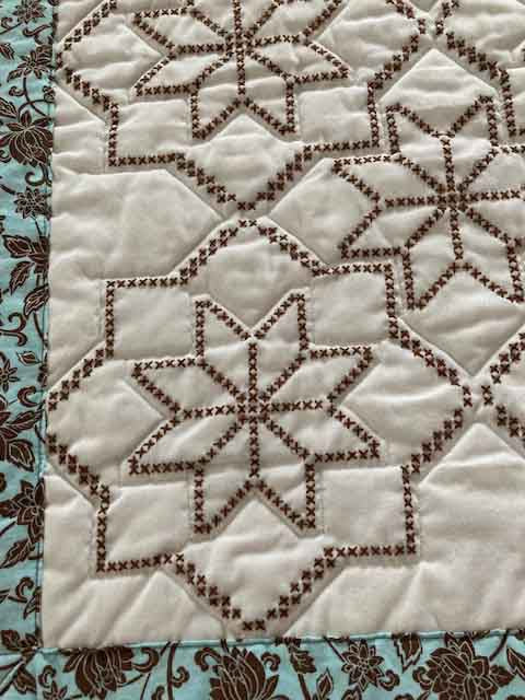 handmade quilt with embroidered blocks of blue and brown