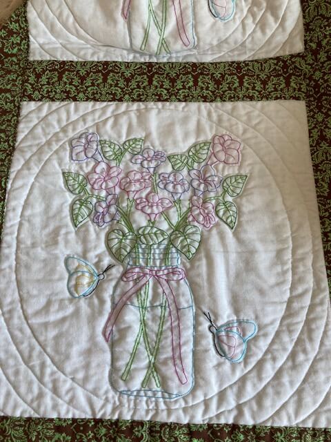 handmade embroidered quilt with pastel flowers in mason jars